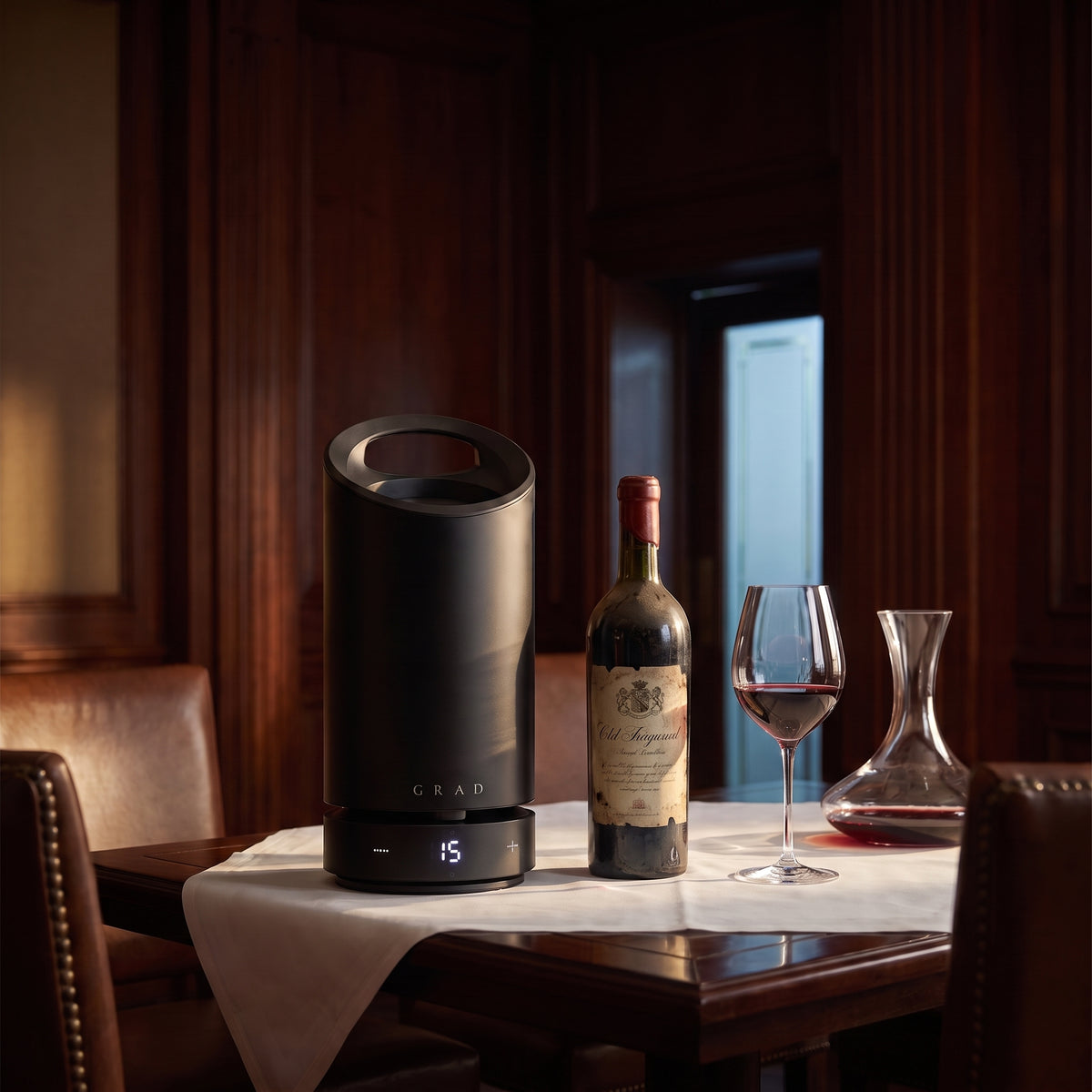 GRAD No.1 Black Edition set to 15 °C next to an aged bottle of red wine, a glass and a decanter in a wood-panelled dining room